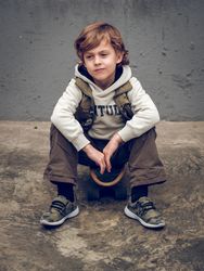 Cute kid sitting on skateboard on street
