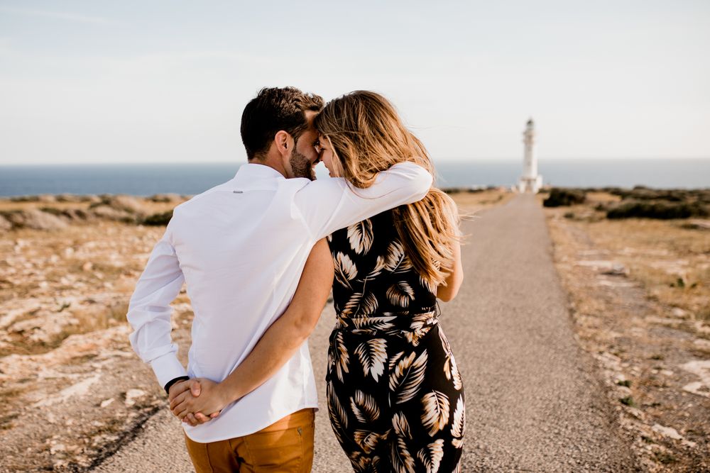 Smiling lovers cuddling on path to sea