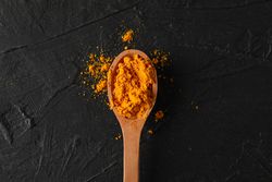 Looking down at wooden spoon of colorful turmeric