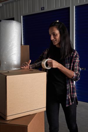 Woman packing belongings with scotch tape