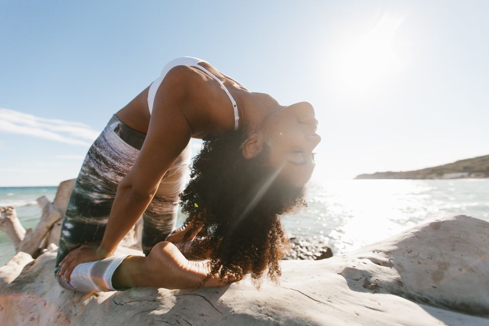 Sportive woman performing yoga posture on stones in nature