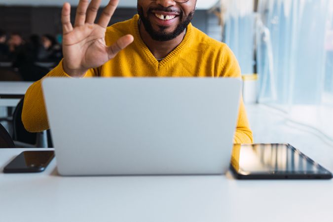 Smiling Black man calling on laptop in workspace