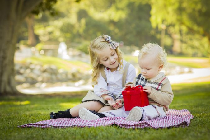 Little Girl Gives Her Baby Brother A Gift at Park.