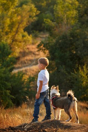 Young boy in jeans walking dog in forest