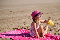 portrait of a little girl with cap and sunglasses at the beach