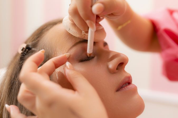 A beautician woman drawing eye shadow at the beauty salon