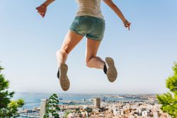 Woman jumping high on beautiful landscape background