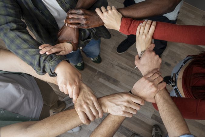 Diverse hands joined together in circle symbolizing unity, teamwork, and collaboration