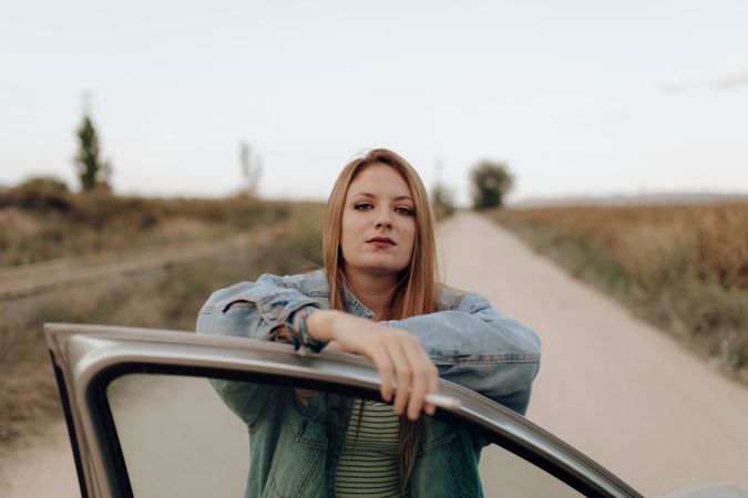 Modern woman with cigarette near car in nature