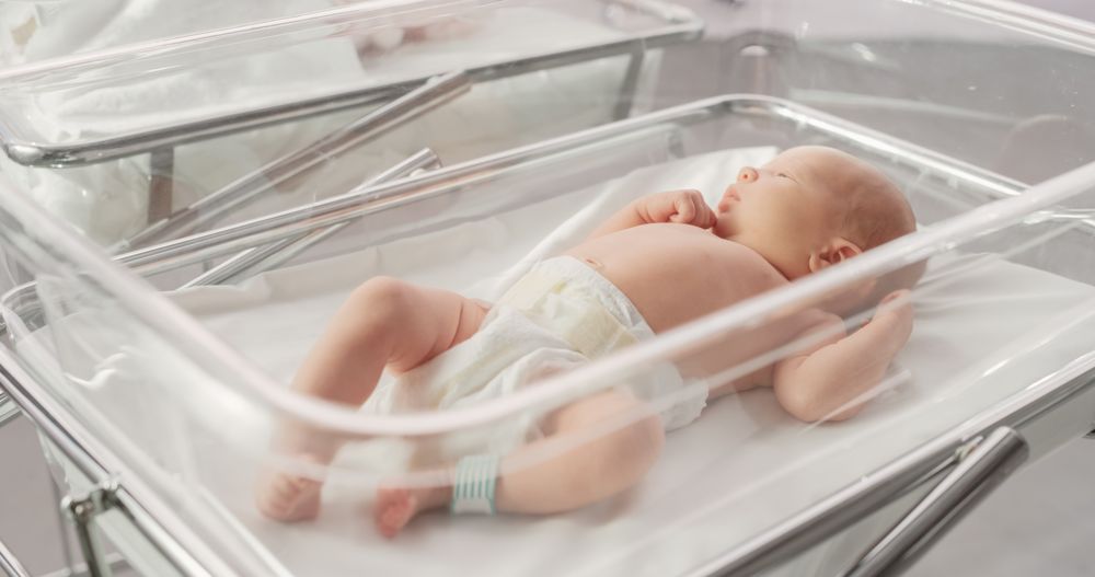 Cute Little Newborn Baby Lying in Bassinet in a Maternity Hospital. Portrait of a Tiny Playful and Energetic Child.