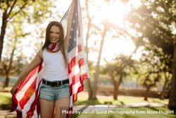 Portrait of a beautiful woman in the park with American flag bGOOYb