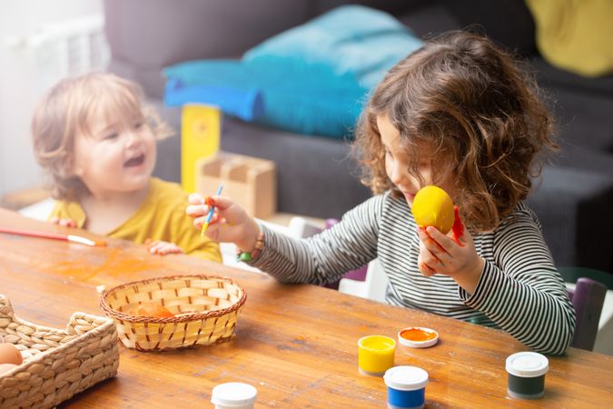 Sisters painting Easter eggs at home