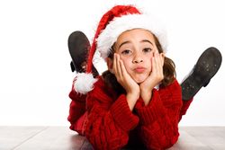 Girl in santa outfit lying on stomach on ground resting her head on her hands