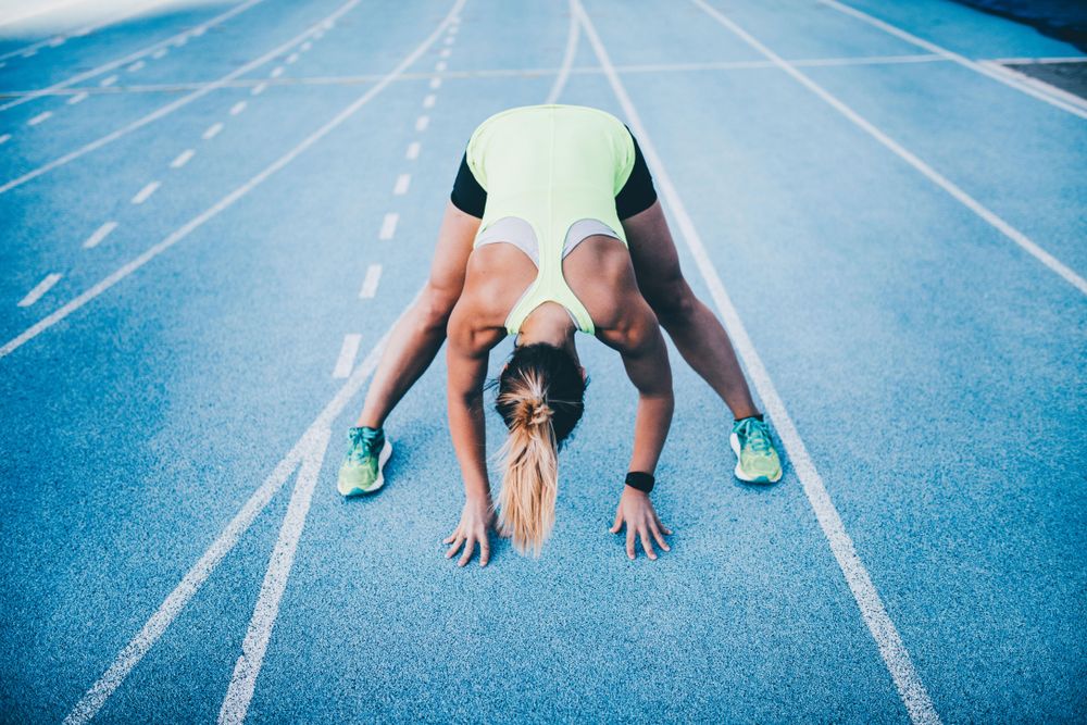 Woman stretching on a track field outside