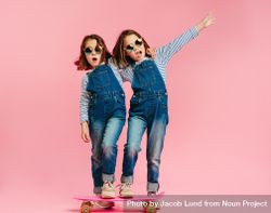 Stylish girls with skateboard and wearing fashion clothes on pink background beNzq0