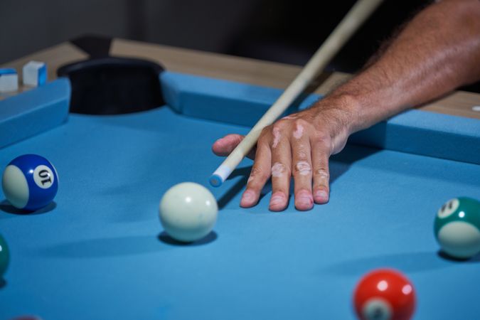Crop man playing billiards at home