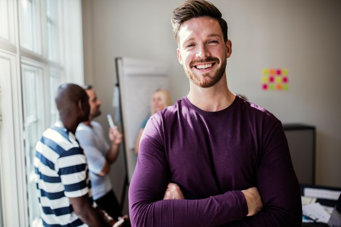 Man in purple shirt smiling with arms folded