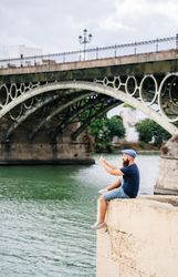 Guy on vacation in casual clothing making photo of bay on smartphone at quay