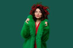 Woman in green coat and red berry wreath