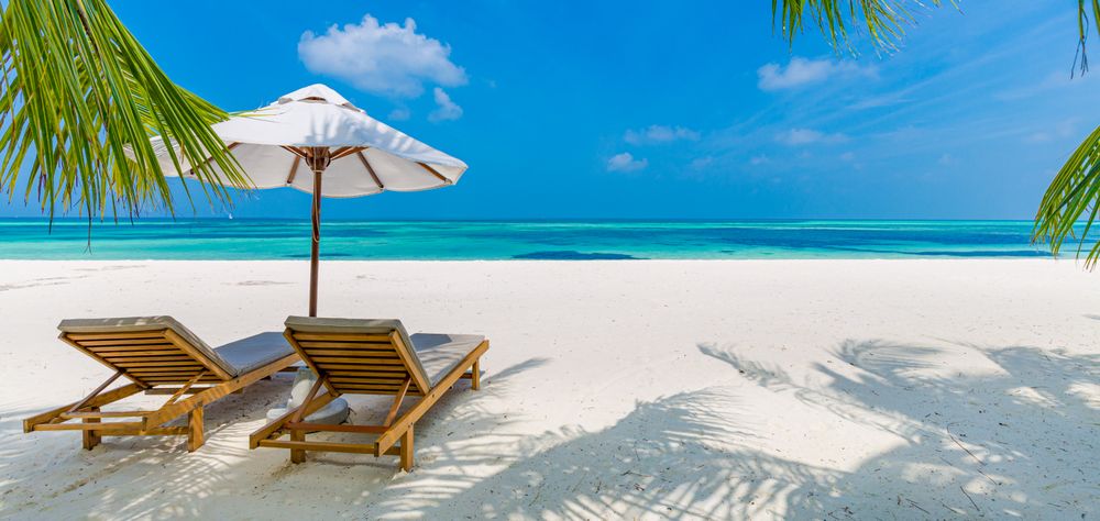 Wide shot of two reclining lounge chairs on an idyllic beach