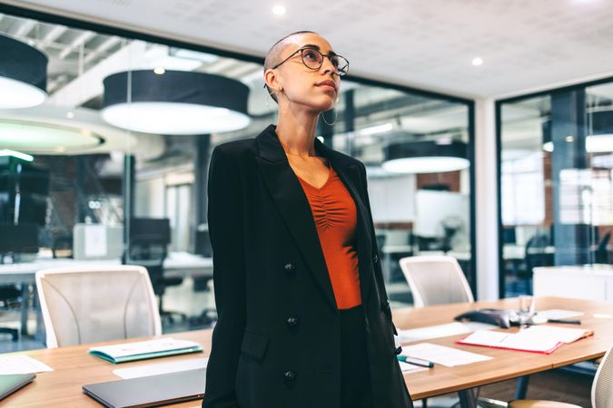 Biracial businesswoman looking thoughtful while standing alone in modern office