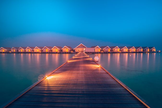 Walkway leading to overwater bungalows lit up at night