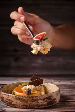 Crop person eating cheesecake with spoon