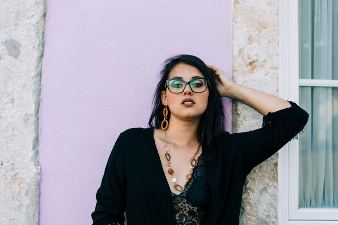 female holding hair against pink wall