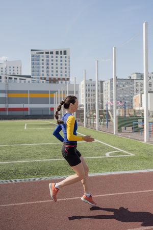 Running young woman in sportswear on stadium
