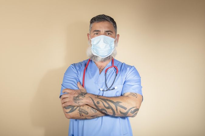 Portrait of doctor with facemask crossing his arms