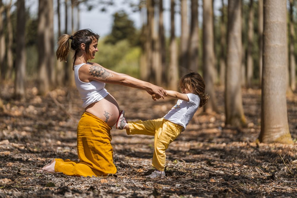 Pregnant mother and little daughter having fun in park