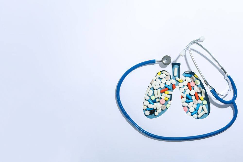 Lung shape cut out of paper with pills underneath with doctor’s stethoscope and copy space