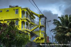 Bright yellow buildings with palm trees against cloudy sky 47EAr0