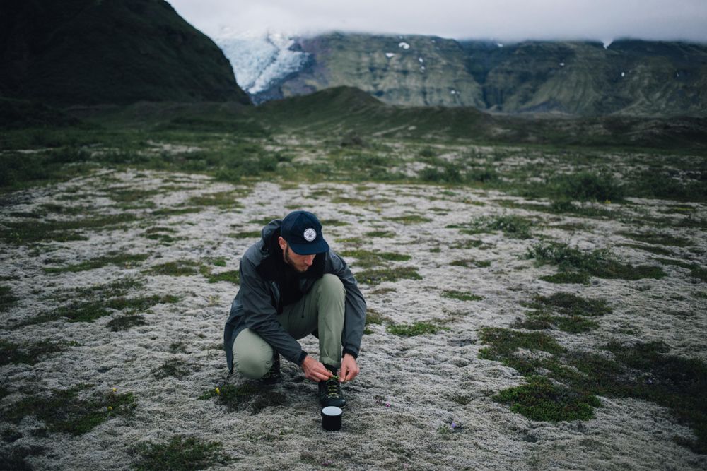 Man tying shoe on overcast day with ceramic mug