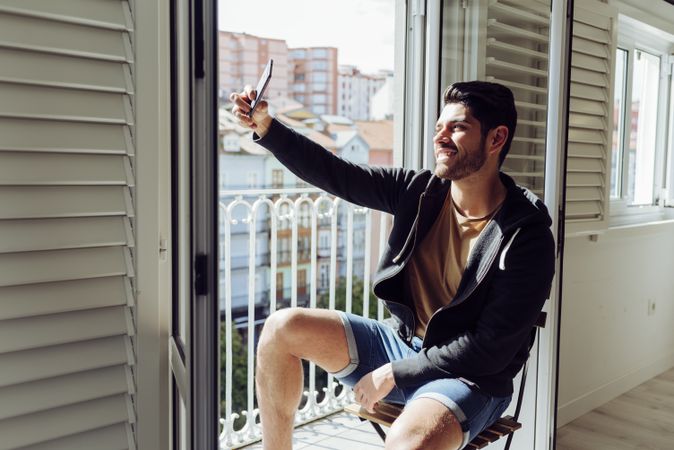 Young cheerful male taking selfie near terrace