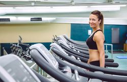 Smiling woman walking on treadmill in gym