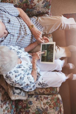 Top view of older couple looking at pictures on digital tablet