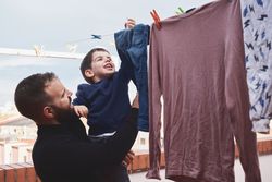 Father and son hanging clothes on rope