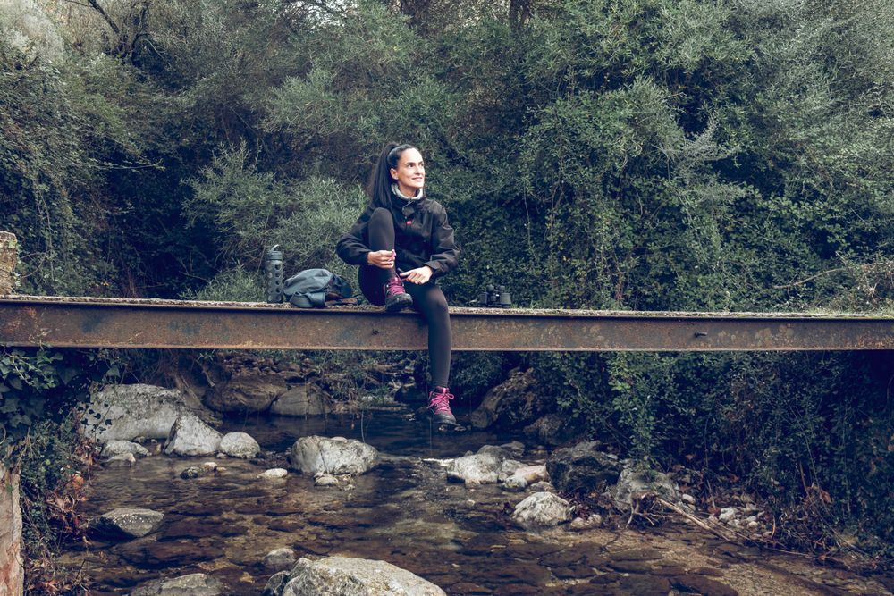 Smiling female relaxing on old bridge during hiking trip in