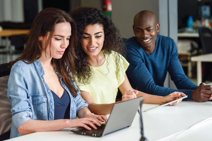 Three young people studying with laptop computer on desk