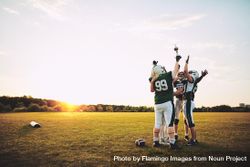 Men with arms and trophy in the air celebrating a win on the football field 0Kly15