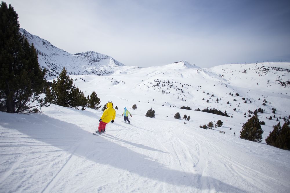 Two snowboarders going down snowy piste in The Alps