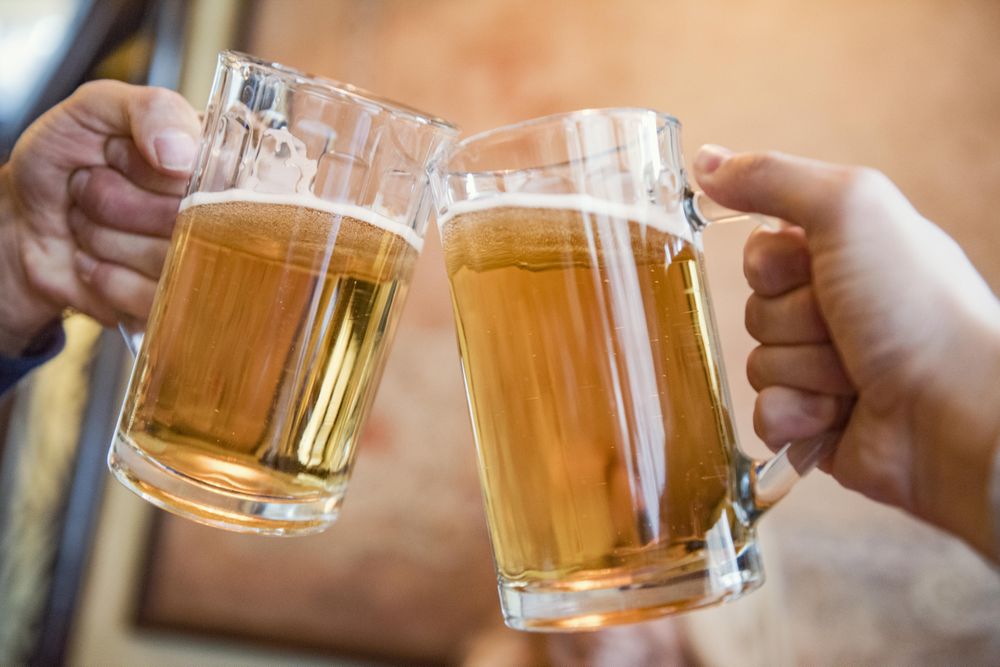 Two people cheering with two pints of beer
