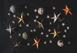 Flat-lay of colorful paper toy decorative stars, with pine cones and baubles
