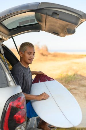 Man with surfboard in car