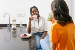 Two women laughing and smiling over coffee in the kitchen