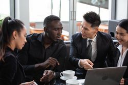 Diverse group of business people having a meeting in coffee shop over laptop