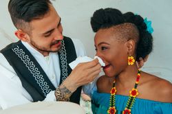 Groom gently wipes wedding cake off the bride with a tissue