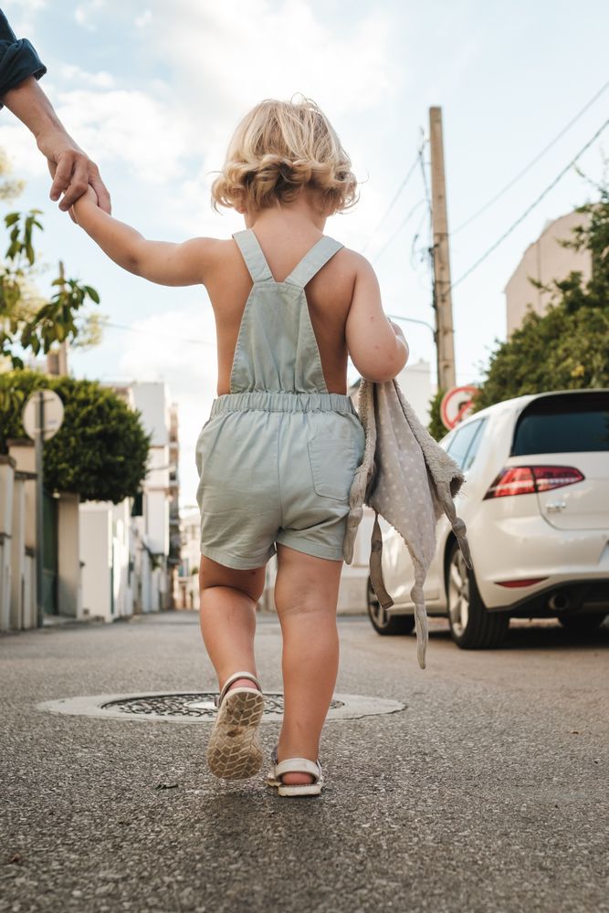Toddler walking on road with parent