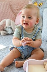 Happy baby with toy on bed at home